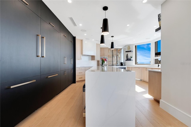 kitchen featuring a kitchen island, modern cabinets, visible vents, and dark cabinets