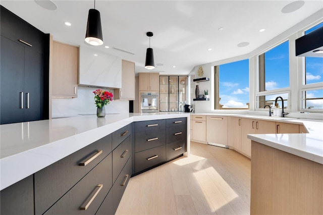 kitchen featuring light wood finished floors, hanging light fixtures, modern cabinets, and light countertops