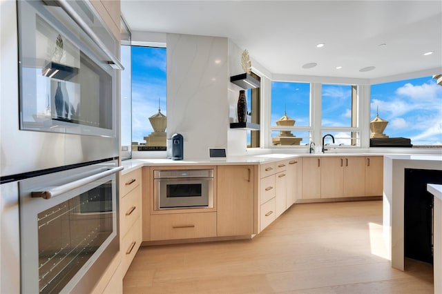 kitchen with light wood-style floors, double oven, modern cabinets, and light brown cabinetry