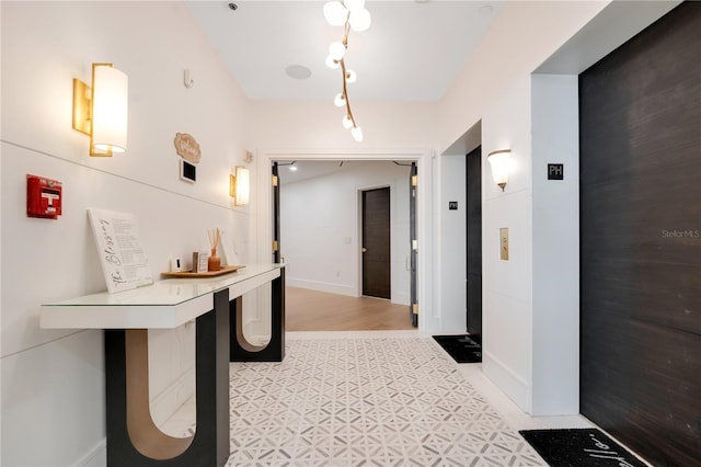 hallway with elevator and baseboards