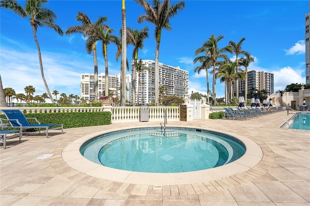 community pool with a patio and fence