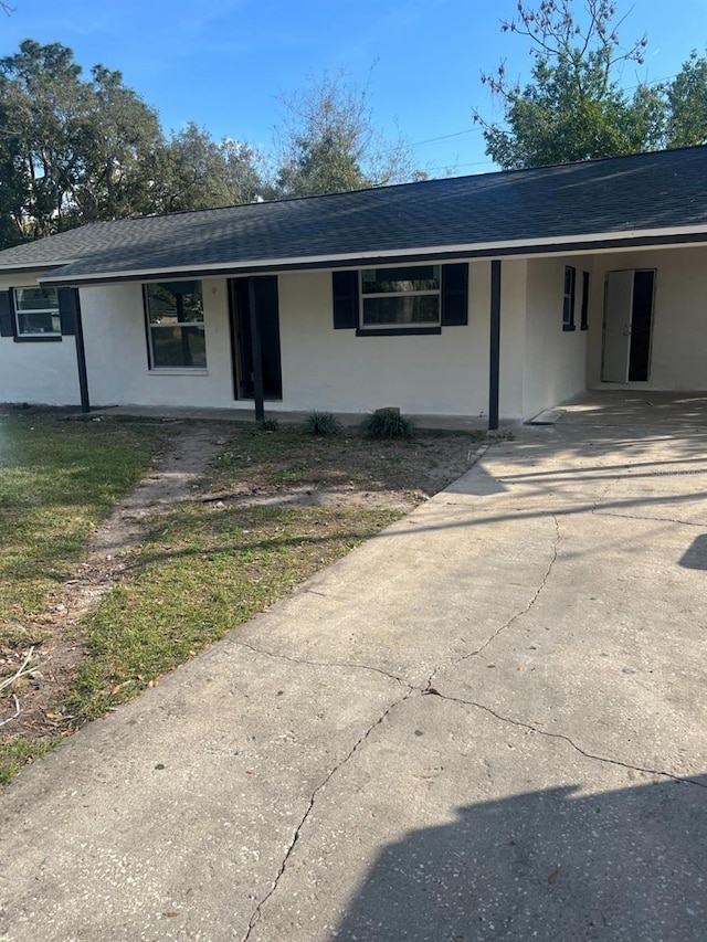 single story home with stucco siding, driveway, and roof with shingles