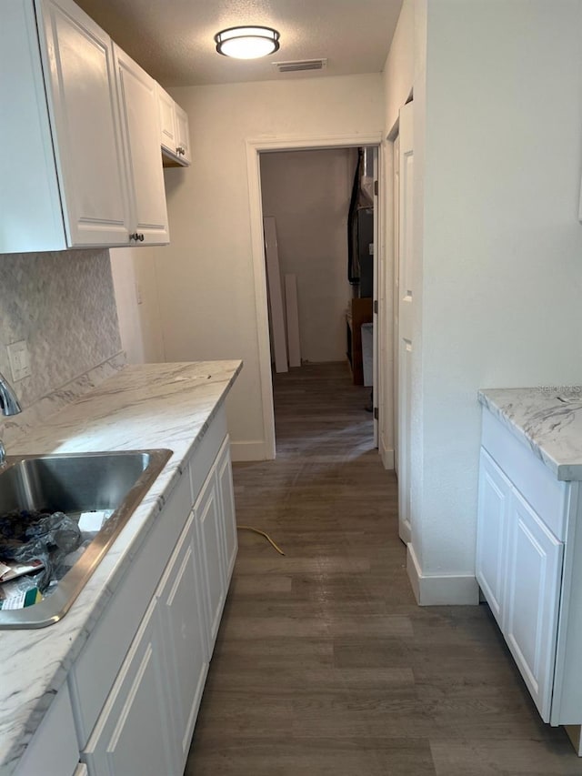 kitchen featuring visible vents, a sink, dark wood-style floors, white cabinets, and decorative backsplash