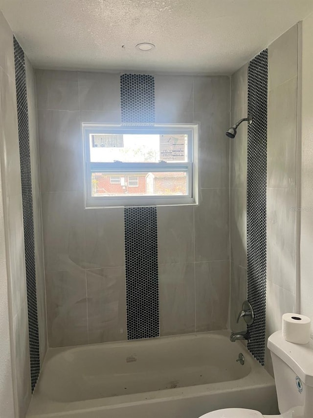 bathroom featuring a textured ceiling, toilet, and  shower combination
