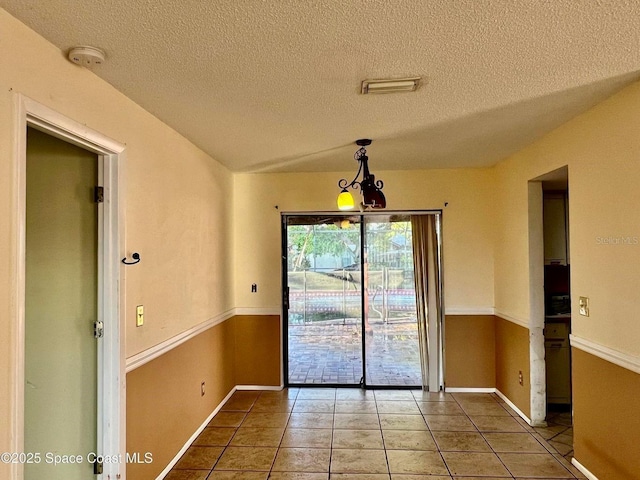 unfurnished dining area with light tile patterned floors and a textured ceiling