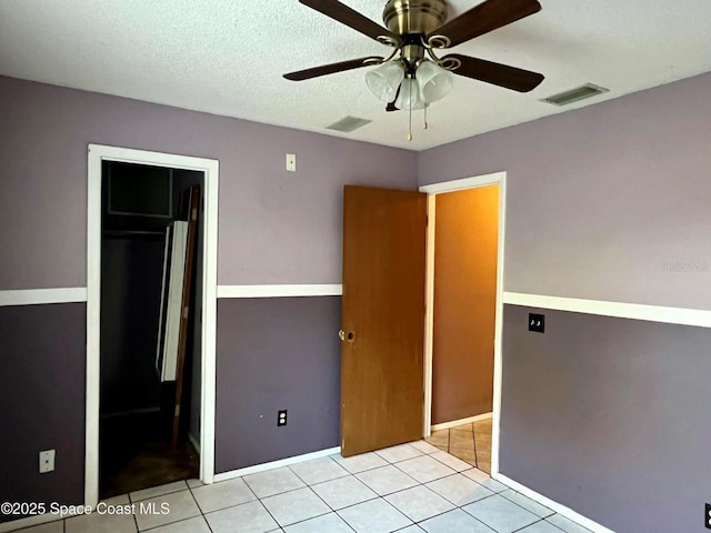 unfurnished bedroom with tile patterned floors, visible vents, a textured ceiling, and ceiling fan