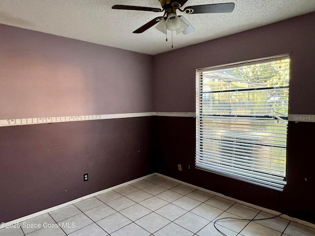 empty room featuring ceiling fan, light tile patterned flooring, and a textured ceiling