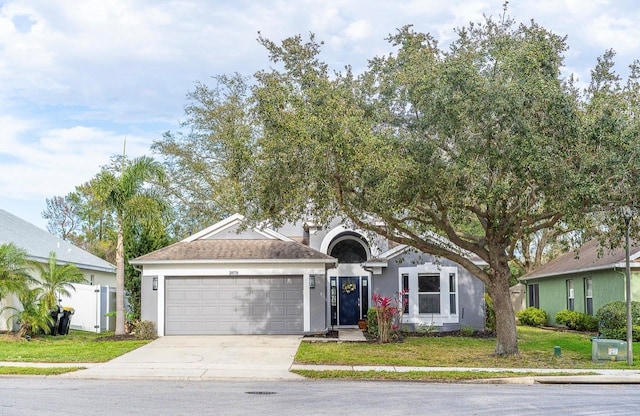 ranch-style home featuring stucco siding, an attached garage, concrete driveway, and a front lawn