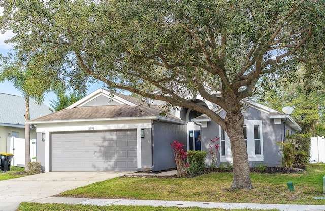 ranch-style home featuring fence, roof with shingles, stucco siding, concrete driveway, and a garage