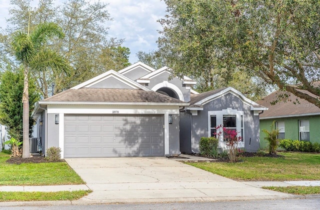 single story home with a front lawn, concrete driveway, roof with shingles, stucco siding, and a garage