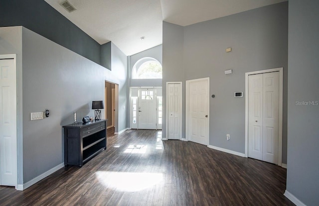 entrance foyer featuring visible vents, baseboards, high vaulted ceiling, and dark wood-style flooring