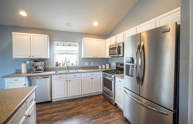 kitchen featuring dark wood finished floors, vaulted ceiling, white cabinets, stainless steel appliances, and a sink