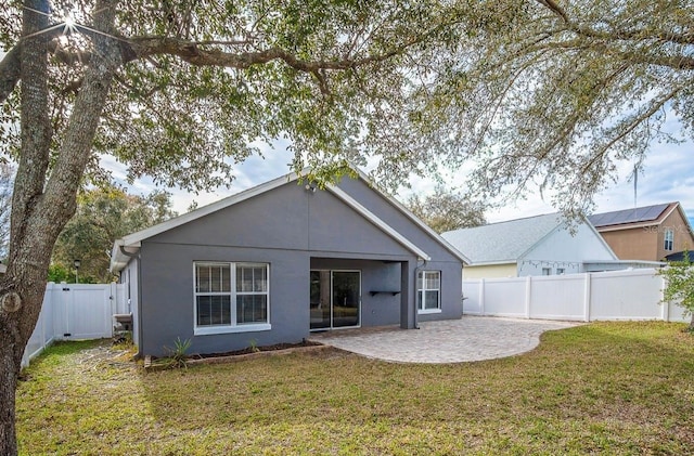 rear view of property with a gate, a yard, a fenced backyard, stucco siding, and a patio area