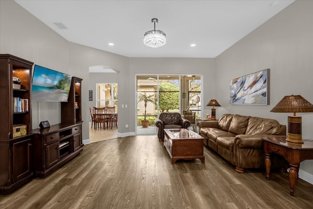 living area with visible vents, arched walkways, baseboards, and wood finished floors