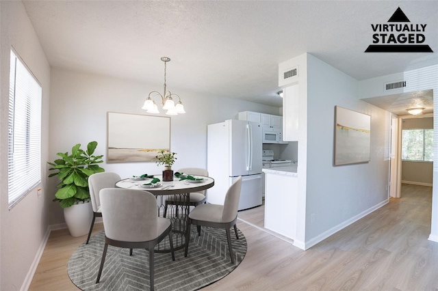 4605 Bayshore Dr Unit 6, Naples, FL 34112 - dining space with light wood finished floors, a chandelier, and a textured ceiling