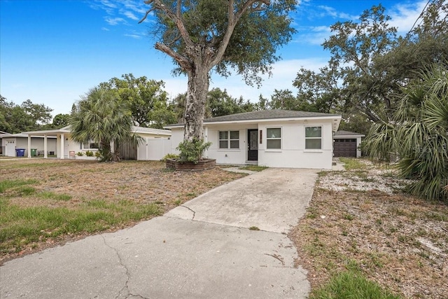 view of front of house with stucco siding, concrete driveway, and fence