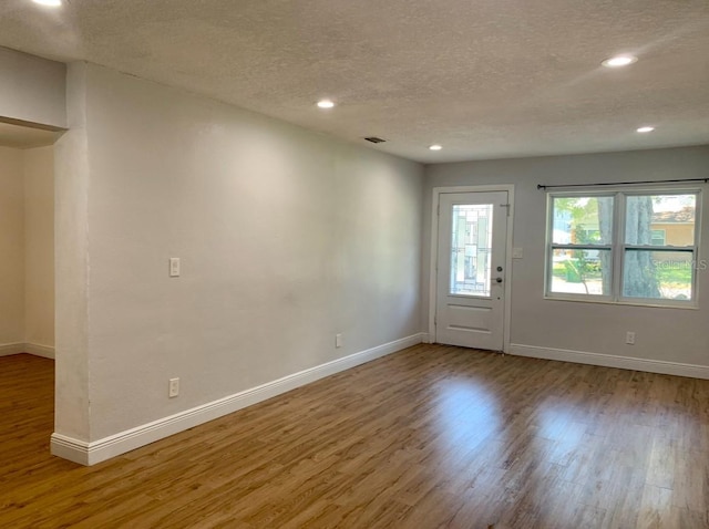 foyer entrance featuring wood finished floors, a textured ceiling, baseboards, and recessed lighting
