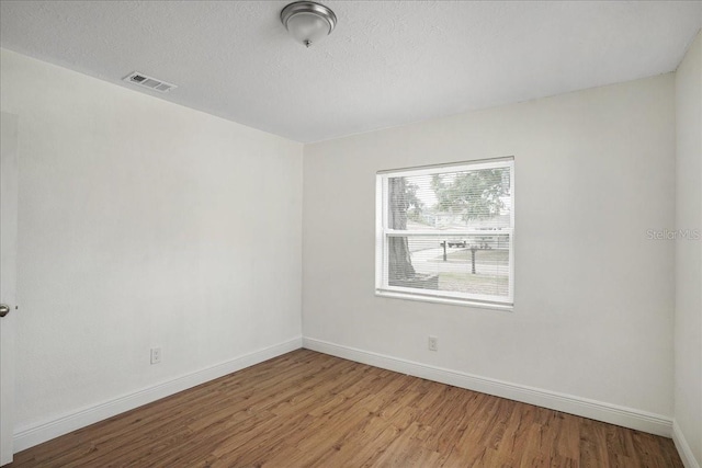 spare room with wood finished floors, baseboards, and a textured ceiling