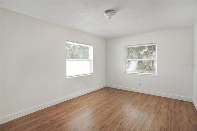 empty room featuring wood finished floors, baseboards, and a textured ceiling
