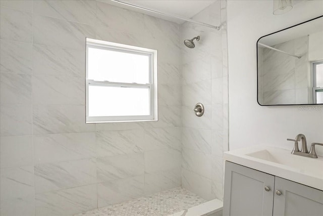 full bathroom featuring tiled shower and vanity