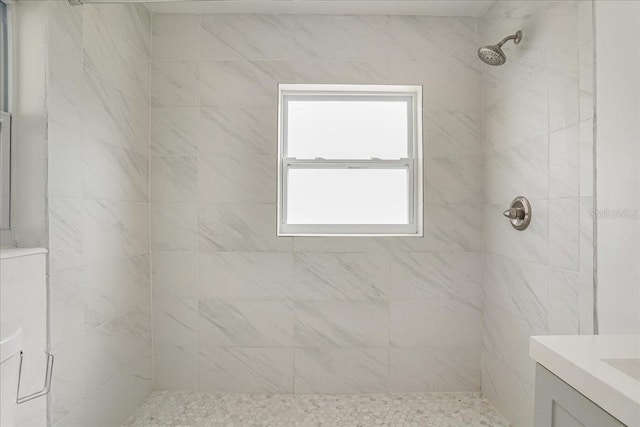 bathroom with a tile shower and vanity