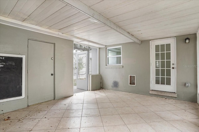 empty room featuring wood ceiling, beam ceiling, and tile patterned flooring