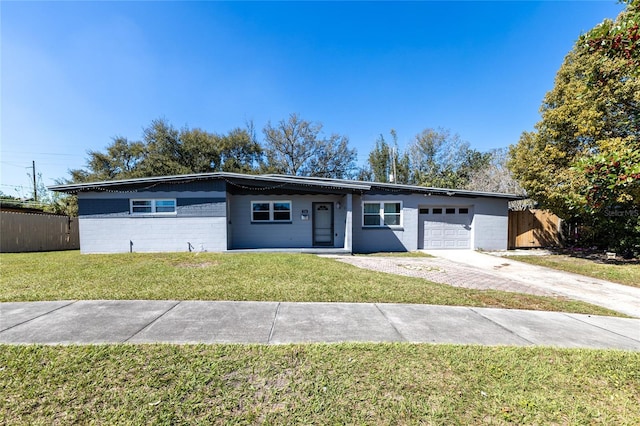 view of front facade featuring concrete block siding, a front yard, fence, driveway, and an attached garage