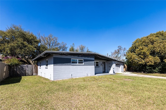 view of front facade with concrete block siding, fence, and a front lawn