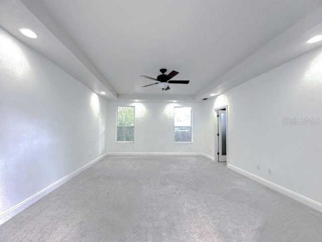 carpeted spare room featuring a tray ceiling, recessed lighting, a ceiling fan, and baseboards