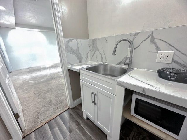 kitchen with tasteful backsplash, dark wood-type flooring, light countertops, and white cabinetry