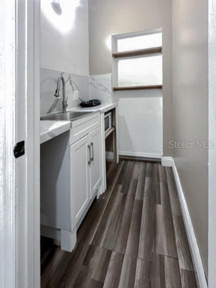 kitchen with a sink, white cabinets, dark wood-style flooring, and light countertops