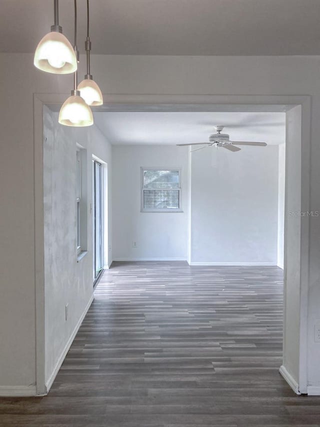 unfurnished room featuring a ceiling fan, baseboards, and wood finished floors