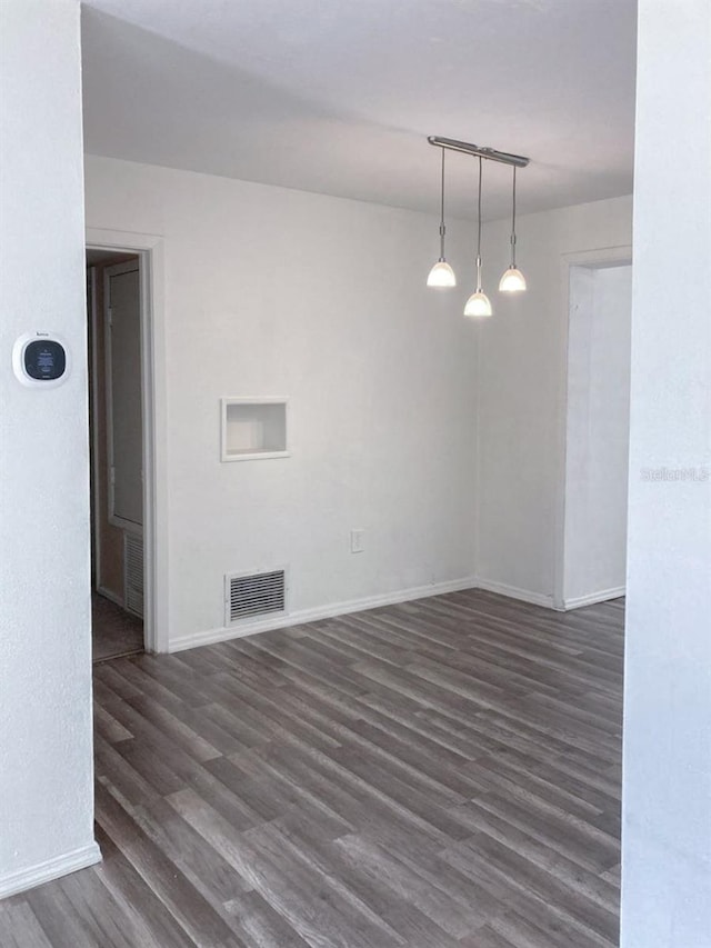 spare room with wood finished floors, visible vents, and baseboards