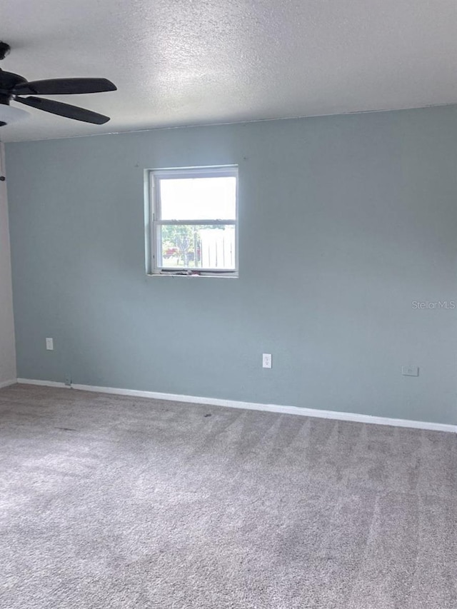 carpeted empty room featuring baseboards, a textured ceiling, and ceiling fan