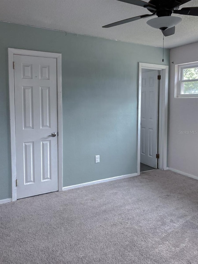 unfurnished room with baseboards, carpet, a ceiling fan, and a textured ceiling