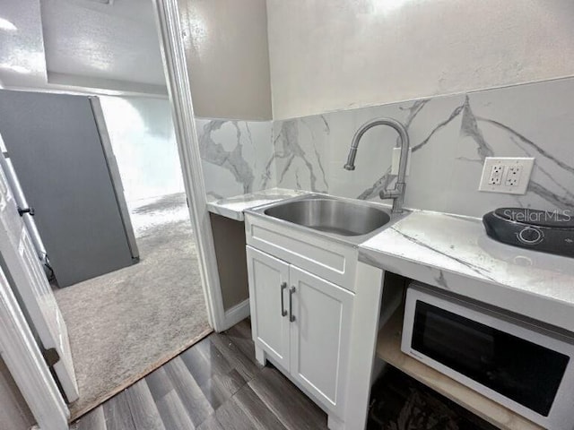 kitchen featuring white microwave, white cabinetry, light countertops, and tasteful backsplash