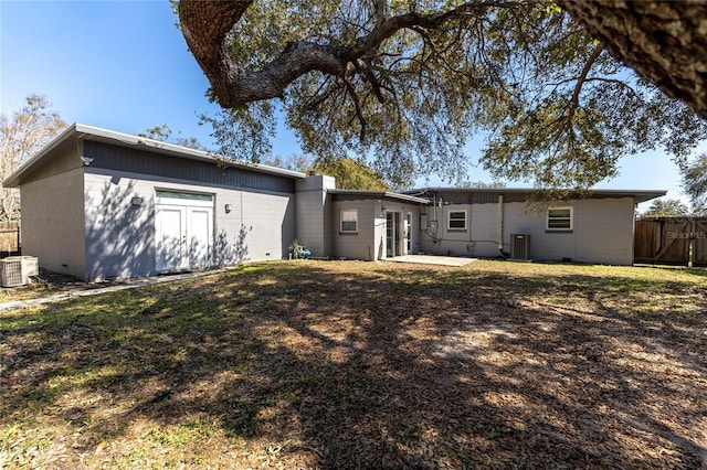 rear view of property featuring central AC unit, a lawn, a patio, and fence