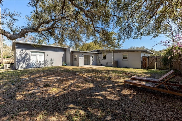 rear view of house with fence, a lawn, and central AC