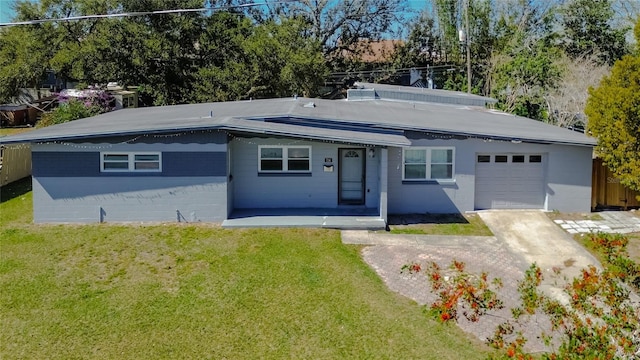 view of front of home with a garage, driveway, concrete block siding, and a front lawn