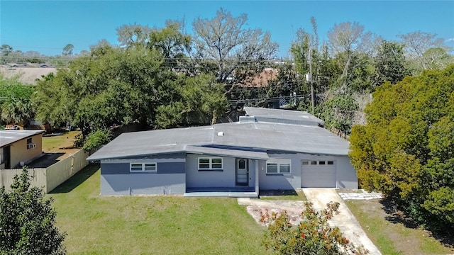 rear view of house with a garage, fence, a lawn, and driveway