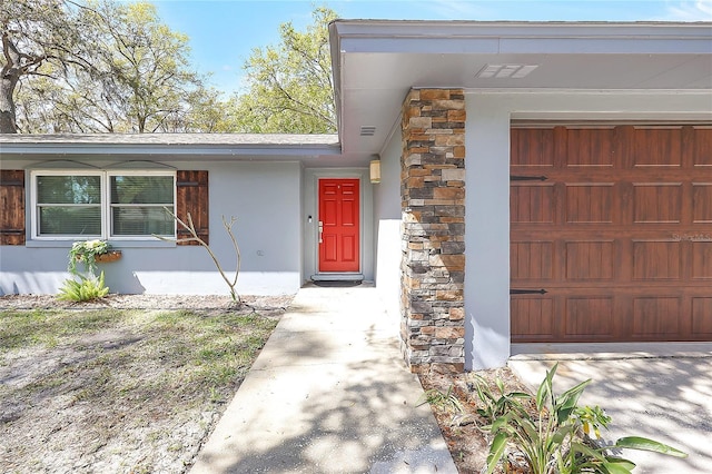 view of exterior entry featuring stone siding and stucco siding