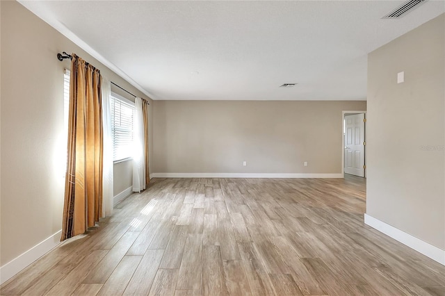 spare room with baseboards, visible vents, and light wood finished floors