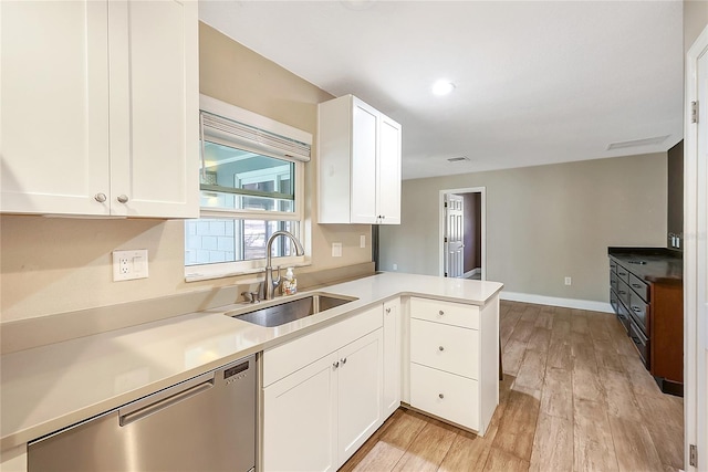 kitchen with a sink, light wood-type flooring, a peninsula, white cabinets, and stainless steel dishwasher