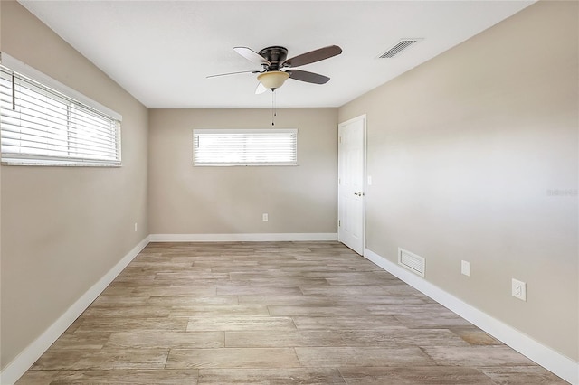 unfurnished room featuring light wood-type flooring, a ceiling fan, visible vents, and baseboards