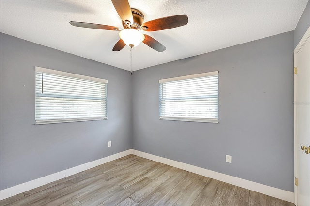 empty room featuring light wood finished floors, baseboards, a textured ceiling, and a ceiling fan