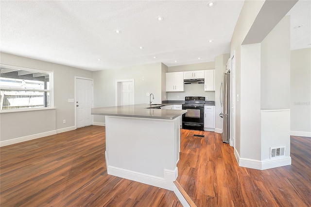 kitchen featuring visible vents, under cabinet range hood, freestanding refrigerator, black / electric stove, and dark wood-style flooring