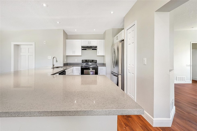 kitchen with black range with electric cooktop, under cabinet range hood, stainless steel fridge, white cabinetry, and a sink