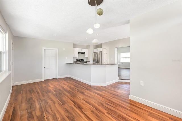 kitchen with white cabinets, dark wood-style floors, baseboards, and freestanding refrigerator