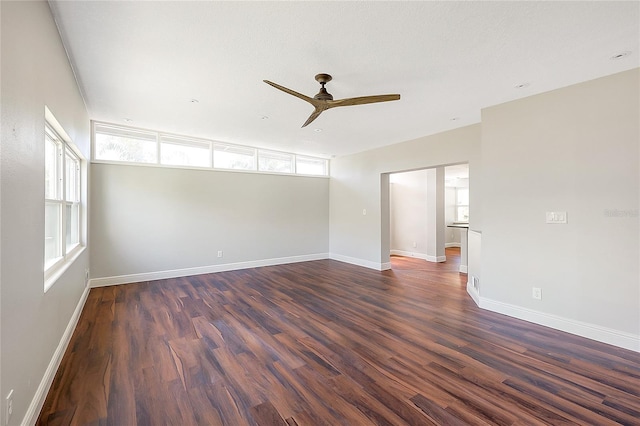 empty room with ceiling fan, baseboards, and dark wood-style floors