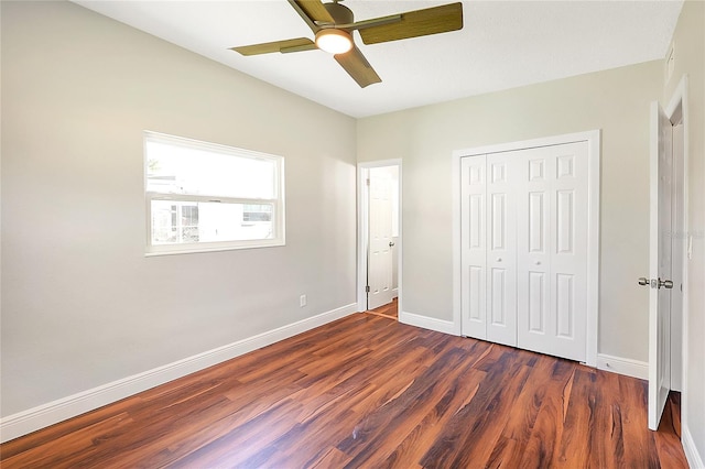 unfurnished bedroom featuring a ceiling fan, dark wood-style floors, baseboards, and a closet